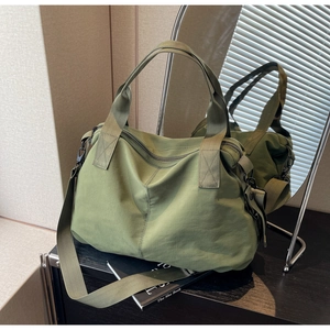 Detail view of large olive nylon travel bag with wide shoulder strap and metal hooks