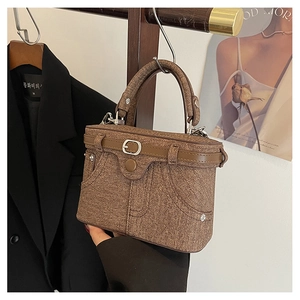 Close-up of vintage brown box bag with twill texture and metallic hardware on hanger