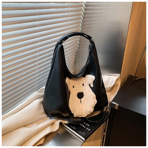 Detail of black PU shoulder bag featuring a large plush dog patch and metal zipper
