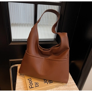 Detail view of large dark brown tote bag showing textured lychee leather and front pocket