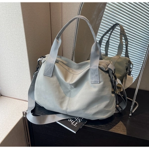 Detailed mirror shot of light blue-grey nylon tote bag with wide strap and silver hooks
