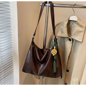 Détail du sac hobo en similicuir marron foncé avec bandoulière réglable et pendentif