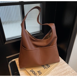 Detailed macro of brown pebble leather texture and front pocket on a tote bag