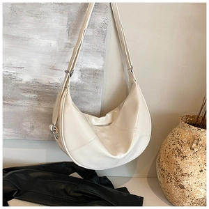 Detail of off-white crescent crossbody bag with geometric stitching and silver hardware