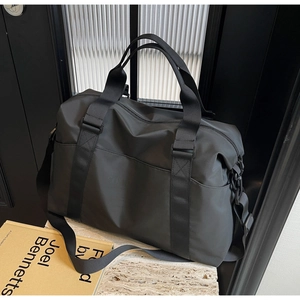 Detail of minimalist black travel bag on stone surface with adjustable shoulder strap