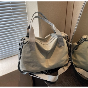 Detail of light khaki tote bag showing waterproof nylon fabric and wide shoulder straps