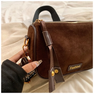 Detail of dark brown cylinder bag with suede texture and woven wide shoulder strap