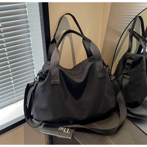 Detail of a large black tote bag with reinforced handles and adjustable strap