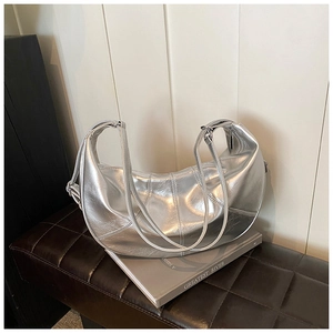 Detailed close-up of metallic silver crescent bag with textured faux leather on a stool