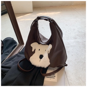 Close-up of brown leather bag with cute plush schnauzer dog motif and silver hardware