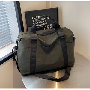 Macro shot of dark green waterproof travel bag showing reinforced handles and front pocket