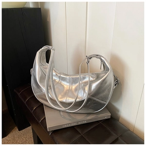 Detail of silver metallic hobo bag with pleated leather texture on a stack of books