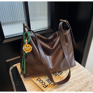 Vue détaillée d'un cabas marron foncé avec pendentif smiley posé sur du marbre poli