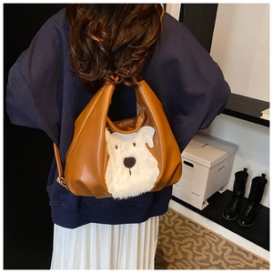 Detail view of brown leather tote bag featuring a cute white plush puppy patch