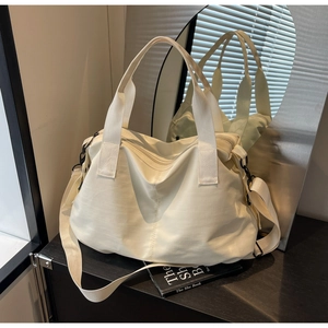 Close-up of cream white tote bag with thick handles and adjustable shoulder strap