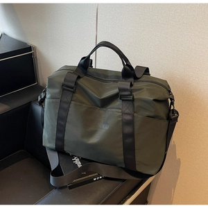 Detail of army green travel bag with Communico text, nylon fabric, and side pocket