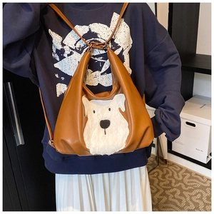 Detail of the brown leather backpack featuring a plush white dog face design and straps