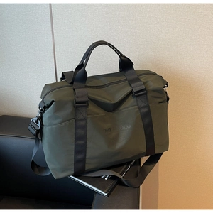 Detail of army green waterproof nylon travel bag with Home Loco logo on black leather sofa