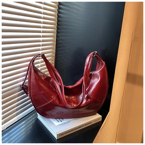 Detail of dark red oil-wax leather hobo bag texture and wide strap on fashion manual
