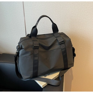Detail view of black travel bag with wide handles and embossed Confidence text