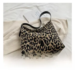 Close-up of leopard print fabric tote bag with black leather strap and metal button