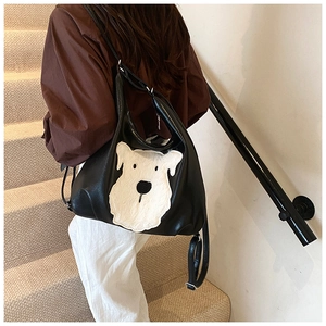 Close-up of black hobo bag with white puppy embroidery and adjustable shoulder strap