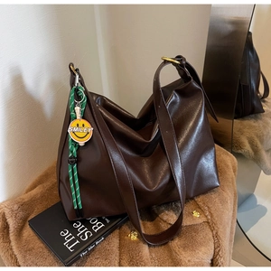 Détail d'un cabas en similicuir marron foncé avec charm Smiley tissé vert