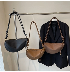 Close-up of three textured leather crescent bags in black, camel, and deep brown colors