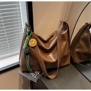 Détail d'un sac cabas marron avec corde tressée verte et pendentif Smiley jaune