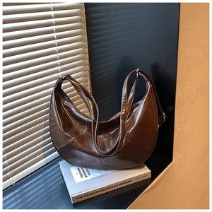 Detail shot of a dark coffee crescent bag with glossy wrinkled leather and thin straps