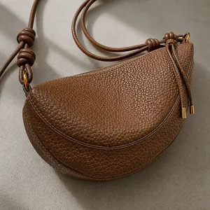 Detail of dark brown litchi grain leather crescent bag with knot shoulder strap design