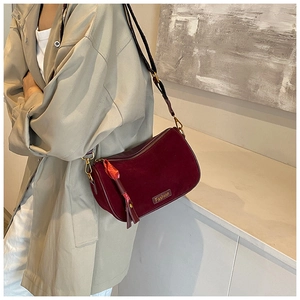 Detail of burgundy velvet pillow bag featuring gold Fashion plaque and tassel