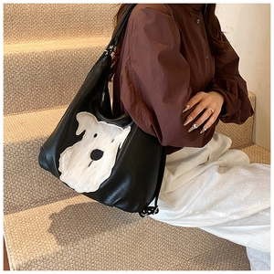 Detail shot of black tote bag featuring a white faux fur schnauzer dog motif and leather texture