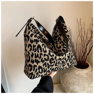 Macro shot of large leopard print tote bag with black leather straps in minimalist studio