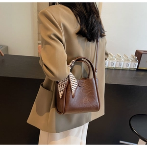 Detail of dark brown vintage texture handbag with checkered scarf on handle and shoulder strap