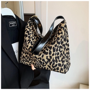 Detail of leopard print fabric tote bag with glossy black leather shoulder strap