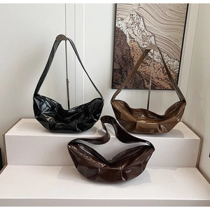 Three pleated leather shoulder bags in black, caramel, and dark brown on a white display
