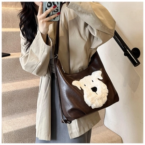 Detail of dark brown PU leather tote bag featuring a white plush dog patch decoration