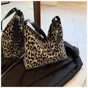 Detail of leopard print tote bag featuring black leather strap and adjustable metal buckle