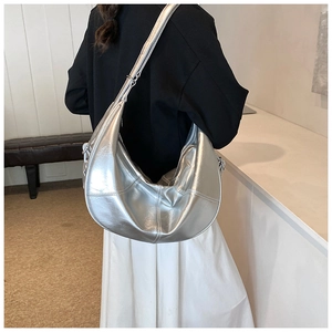 Detailed back view of a silver metallic hobo bag worn over the shoulder by a model