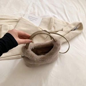 Détail de la texture douce en fausse fourrure marron et poignée en cuir du sac d'hiver