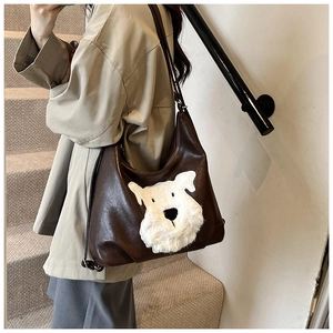 Close-up of brown PU leather shoulder bag with white plush dog patch on modern stairs