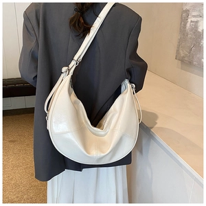 Side view of a creamy white large hobo bag with adjustable strap on a female model