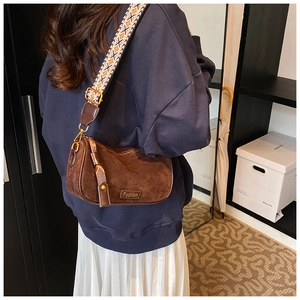 Detail of dark brown suede shoulder bag featuring a patterned wide fabric strap