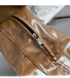 Close-up of a smooth metal zipper on a dark brown pleated dumpling bag with lychee texture