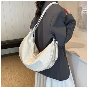 Detail of a minimalist cream crescent shoulder bag with glossy leather and wide strap