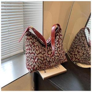 Detail of red leopard print jacquard fabric and sleek leather strap on bucket bag