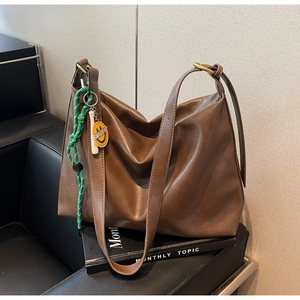 Vue détaillée du grand sac cabas en cuir marron avec un charme smiley jaune sur un canapé