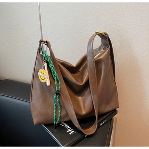 Détail du sac fourre-tout marron foncé avec large sangle et breloque smiley jaune