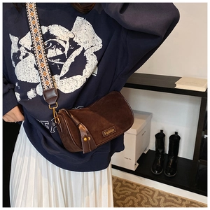 Detail of brown suede pillow bag with vintage metal buckle and geometric strap